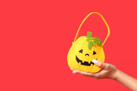 Female hand with Halloween bag on red background, closeupの写真素材