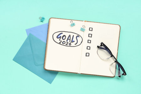 Notebook with 2026 goals, eyeglasses and envelopes on green backgroundの写真素材