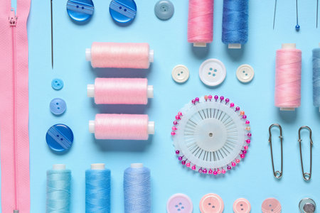 Set of thread spools with sewing supplies on blue backgroundの写真素材