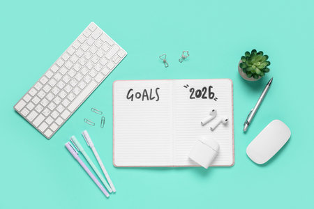 Notebook with 2026 goals, earphones and computer keyboard on green backgroundの写真素材