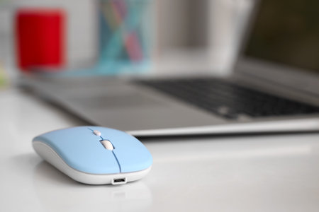 Modern computer mouse with laptop on table in officeの写真素材