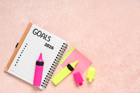 Notebook with 2026 goals, markers and sticky paper on pink grunge backgroundの写真素材