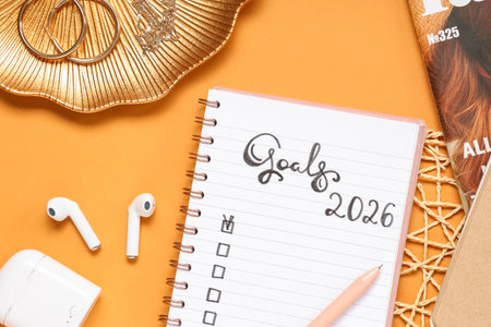 Notebook with 2026 goals, earphones and accessories on orange backgroundの写真素材