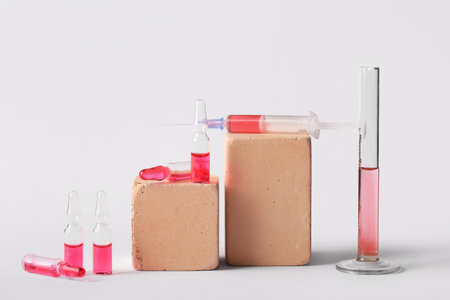 Glass ampoules with syringe and test tube on light background