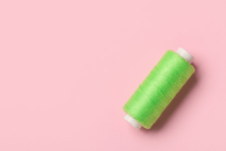 Green sewing thread spool on pink background, closeupの写真素材