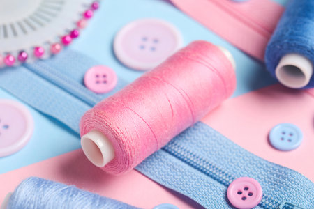 Composition with thread spools, zippers and buttons on color background, closeupの写真素材