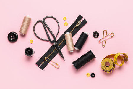 Composition with thread spools, scissors and buttons on pink backgroundの写真素材