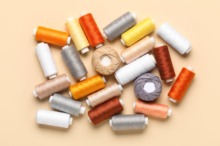 Composition with different thread spools on beige background, closeup