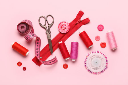 Composition with thread spools, scissors and buttons on pink backgroundの写真素材