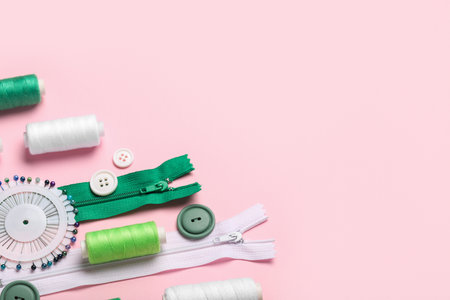 Composition with thread spools, zippers and buttons on pink background, closeupの写真素材