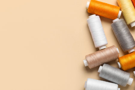 Composition with different thread spools on beige background, closeup