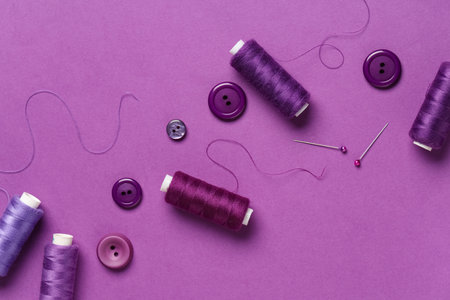 Spools of thread with ball pins and buttons on purple backgroundの写真素材