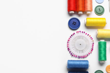 Composition with different thread spools, ball pins and buttons on white background, closeupの写真素材
