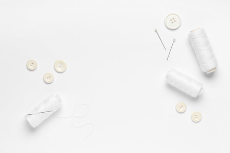 Spools of thread with buttons and ball pins on white backgroundの写真素材