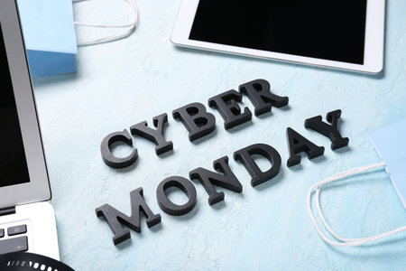 Text CYBER MONDAY with gadgets and shopping bags on light grunge background, closeupの写真素材