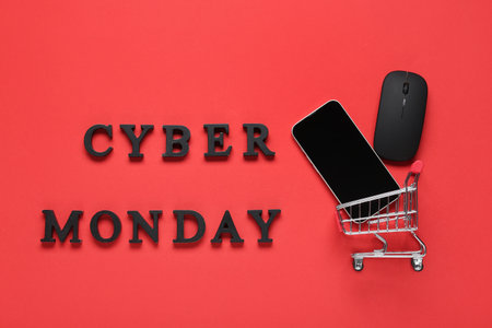 Text CYBER MONDAY and shopping cart with gadgets on red backgroundの写真素材