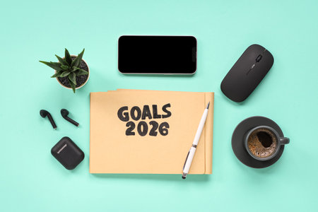 Notebook with 2026 goals, earphones, mobile phone and coffee on green backgroundの写真素材