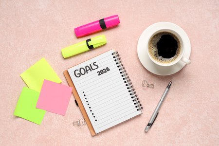Notebook with 2026 goals, sticky papers, markers and coffee on pink grunge backgroundの写真素材