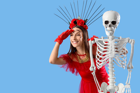 Young happy woman dressed for Halloween with skeleton on blue backgroundの写真素材