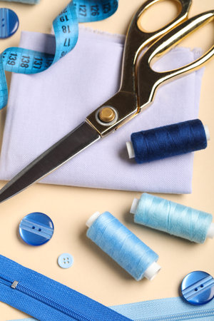 Composition with thread spools, fabric, buttons and scissors on beige background, closeupの写真素材