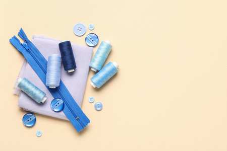 Composition with thread spools, fabric and buttons on beige backgroundの写真素材