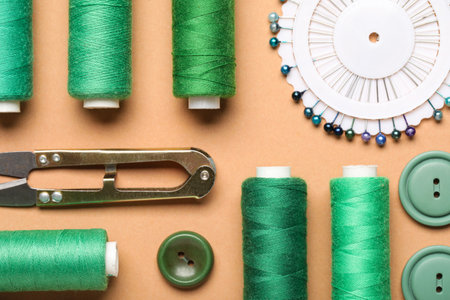Composition with green thread spools, ball pins and buttons on beige background, closeupの写真素材