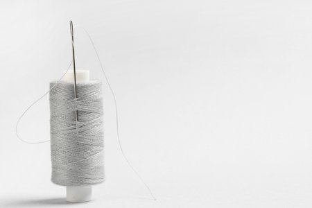 Spool of thread with needle on gray backgroundの写真素材