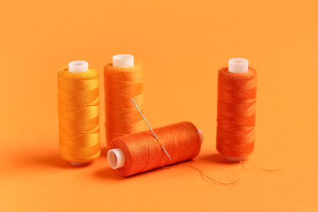 Spools of thread with needle on orange backgroundの写真素材
