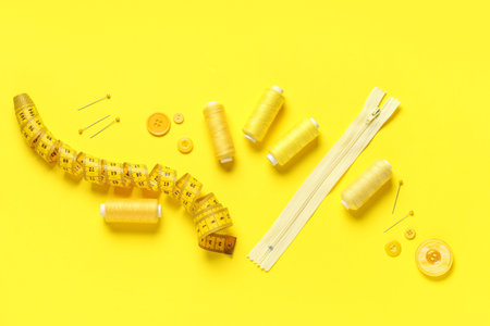 Spools of thread and sewing supplies on yellow backgroundの写真素材