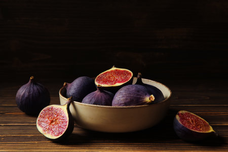Bowl with fresh ripe figs on brown wooden table, closeupの写真素材