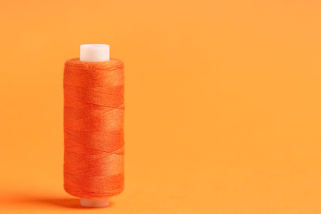 Spool of thread on orange background