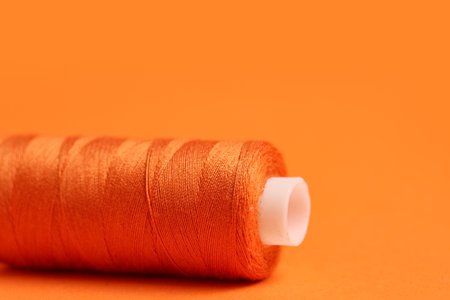 Spool of thread on orange background, closeupの写真素材