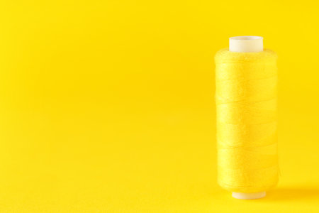 Spool of thread on yellow backgroundの写真素材