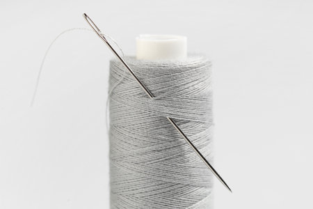 Spool of thread with needle on gray backgroundの写真素材
