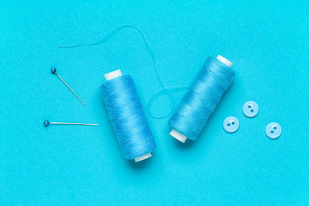 Spools of thread with ball pins and buttons on blue background