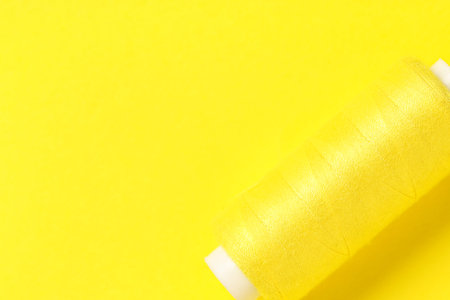 Spool of thread on yellow background