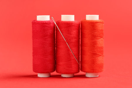 Spools of thread with needle on red backgroundの写真素材
