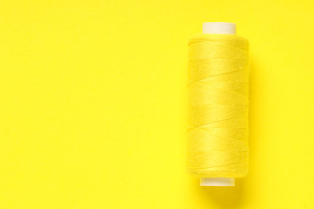 Spool of thread on yellow background