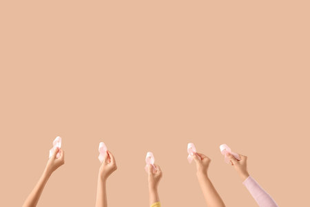 Many female hands with pink awareness ribbons on beige background. Breast cancer conceptの写真素材