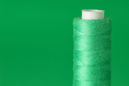 Spool of thread on green background, closeup