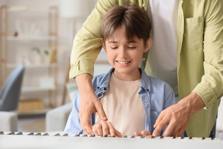 Private music teacher giving synthesizer lessons to boy at homeの写真素材