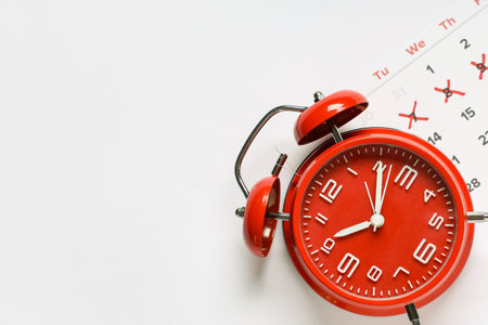 Calendar with alarm clock on white background
