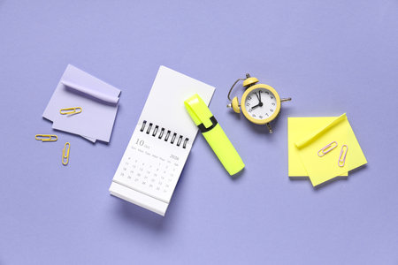Calendar with alarm clock and stationery on purple backgroundの写真素材