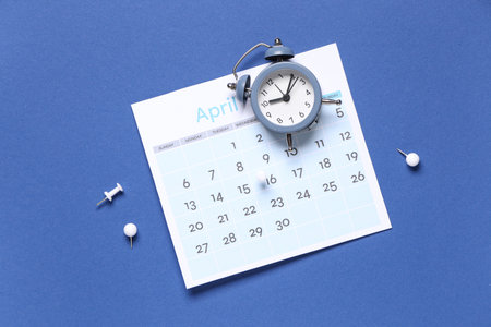 Calendar with alarm clock and paper pins on blue backgroundの写真素材