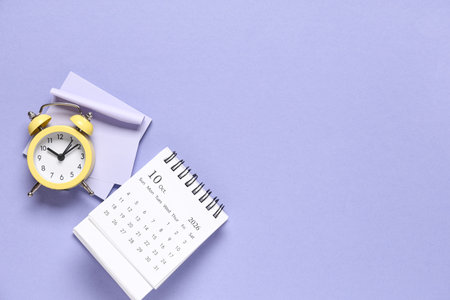 Calendar with alarm clock and sticky notes on purple backgroundの写真素材