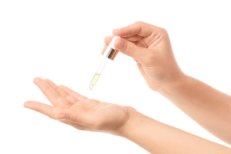 Female hands applying essential oil on white backgroundの写真素材