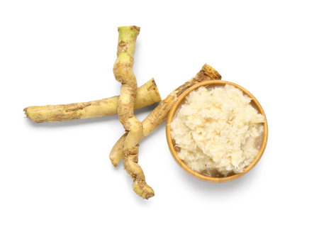 Wooden bowl of horseradish sauce with root on white backgroundの写真素材