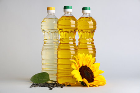 Bottles of oil with sunflower and seeds on white backgroundの写真素材