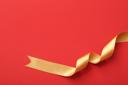 Golden satin ribbon on red backgroundの写真素材