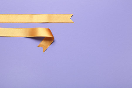 Golden satin ribbons on purple backgroundの写真素材